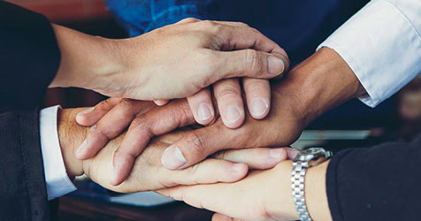 Team of people with their hands stacked on top of each other in a huddle